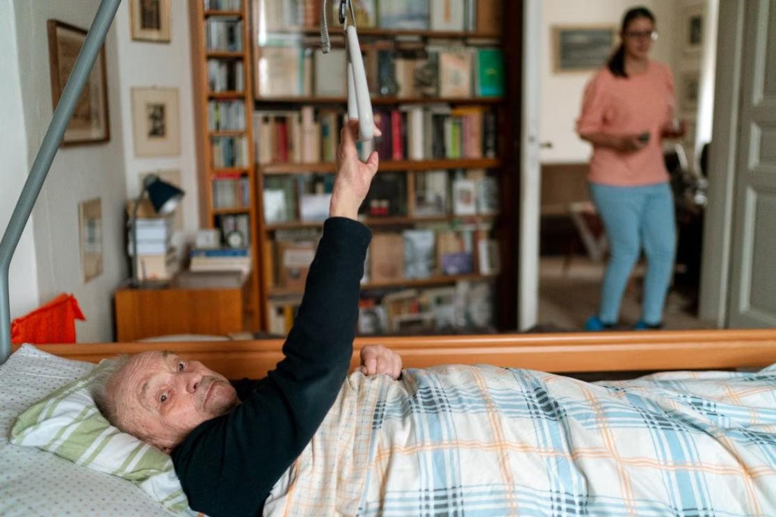 A caregiver at a client's home while he rests comfortably in bed